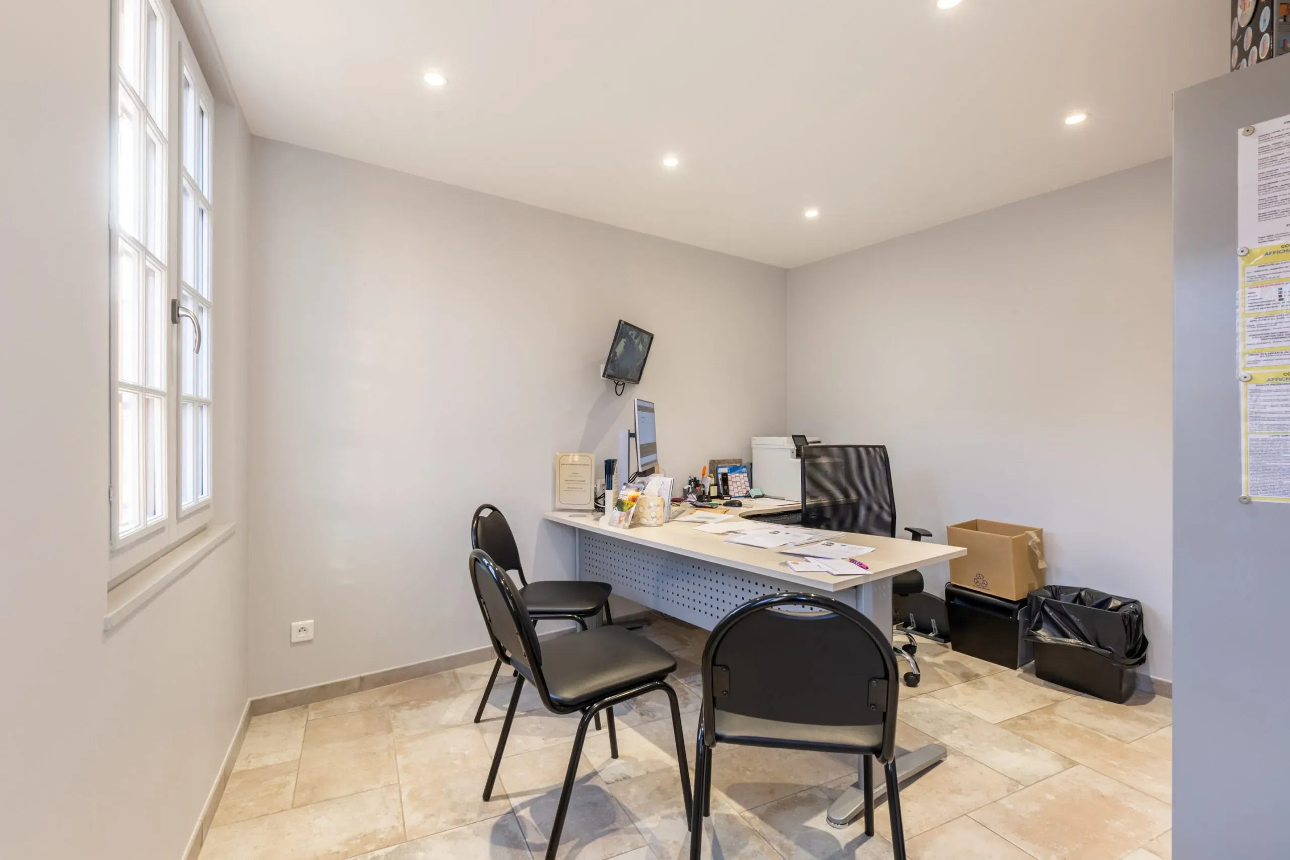 Bureau d'accueil funéraire avec bureau, chaises et ordinateur.