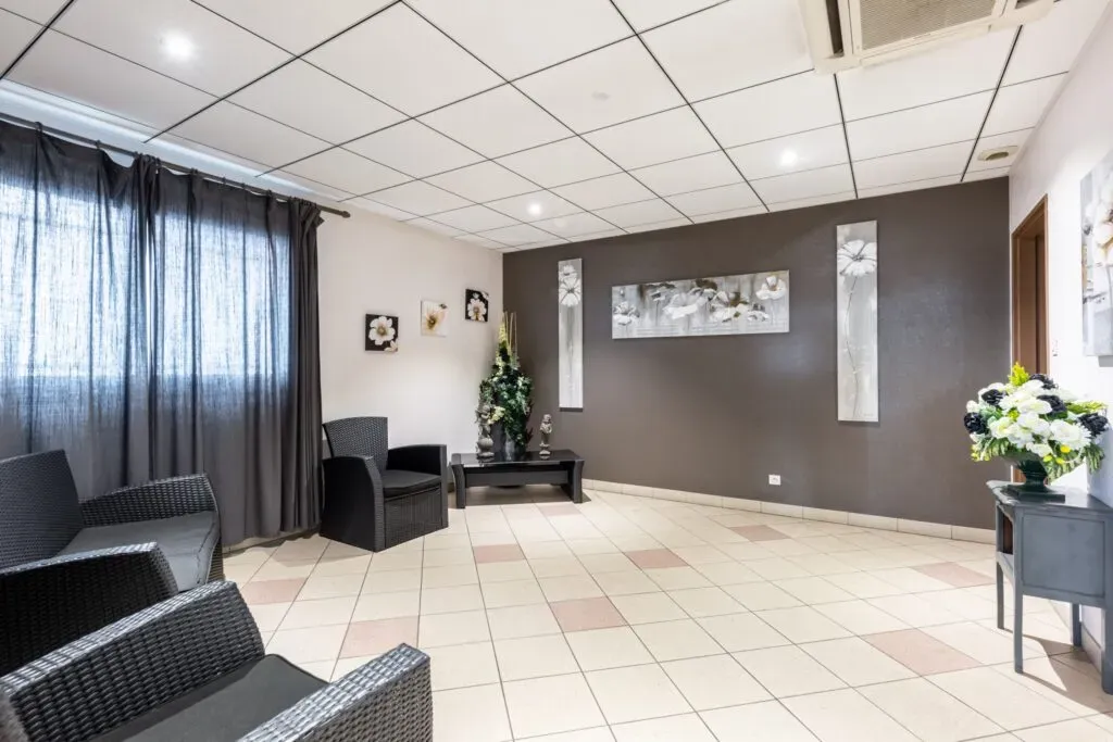 Salon de recueillement funéraire moderne avec fauteuils noirs pour les familles.