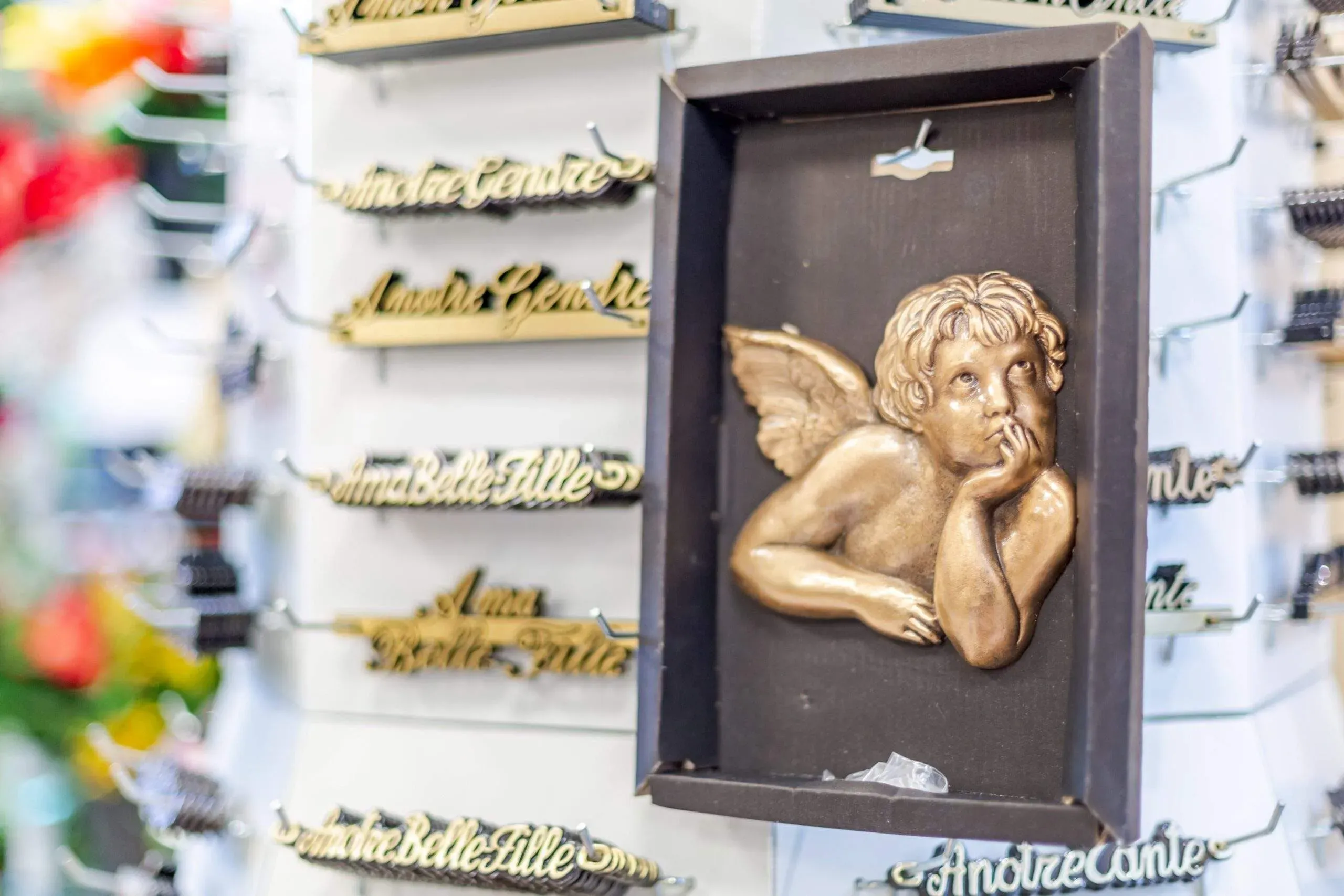 Inscriptions funéraires dorées et buste d'ange pensif en bronze sur présentoir.